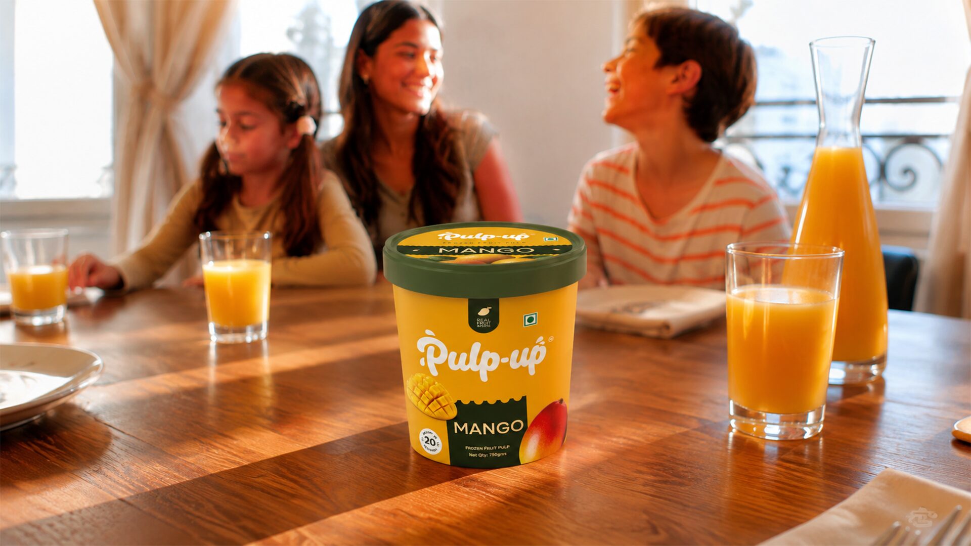 A family at a sunlit table with mango juice and a Pulp-up tub